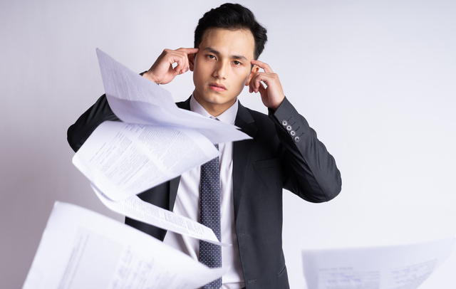 Image of a stressed businessman with paperwork.