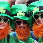 Three people in green st patricks hats, green heart-shape glasses and red beards.