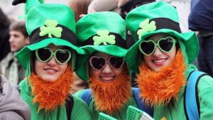 Three people in green st patricks hats, green heart-shape glasses and red beards.