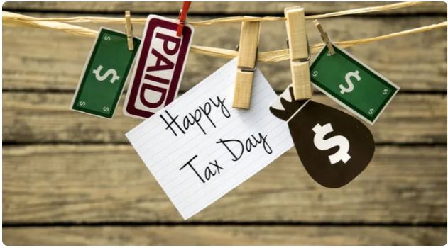 A note that says Happy Tax Day hanging from a clothes pin on a line.